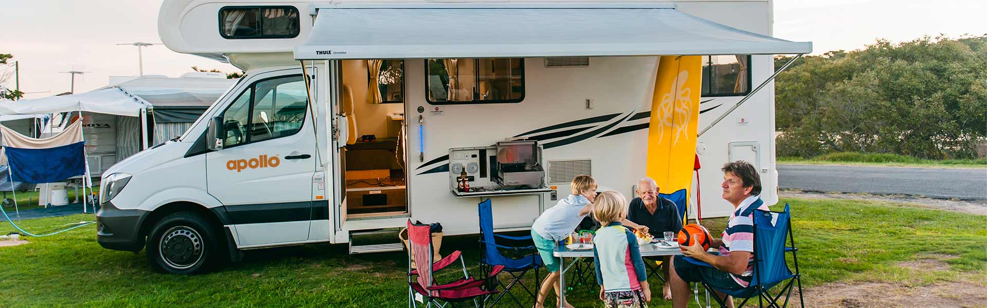family sitting in front of campervan 
